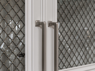 Details on the Top Knobs Ascendra pull in Brushed Satin Nickel on open framed doors with glass panels and decorative metal meshing overlay